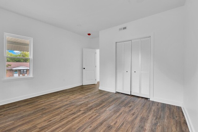 unfurnished bedroom featuring baseboards, a closet, visible vents, and dark wood-style flooring