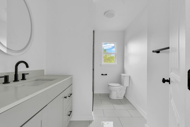 bathroom featuring toilet, tile patterned floors, baseboards, and vanity