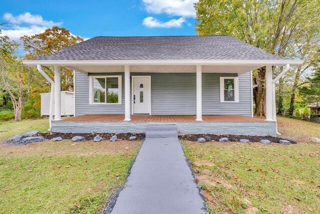 view of front of property with covered porch, a shingled roof, and a front lawn