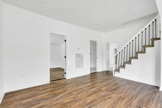 spare room featuring dark wood-style floors, stairway, visible vents, and baseboards