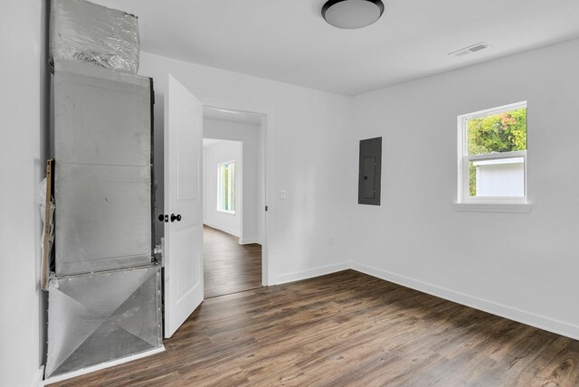 unfurnished room featuring plenty of natural light, electric panel, baseboards, and dark wood finished floors