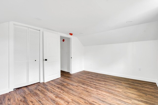 additional living space with dark wood-style floors, vaulted ceiling, and baseboards