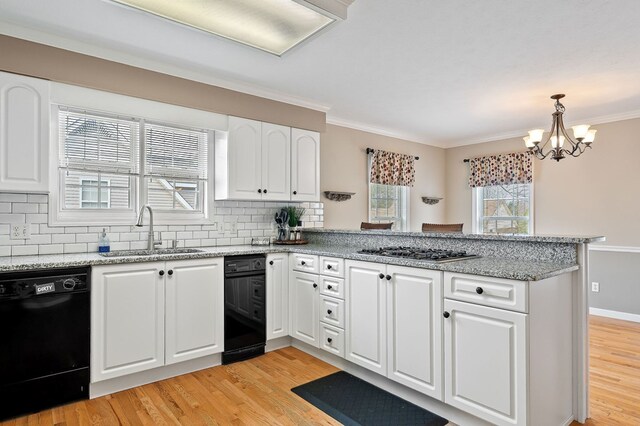 kitchen featuring pendant lighting, black dishwasher, stainless steel gas cooktop, white cabinets, and a sink