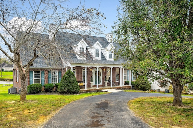 cape cod-style house featuring a front yard, brick siding, driveway, and central AC unit