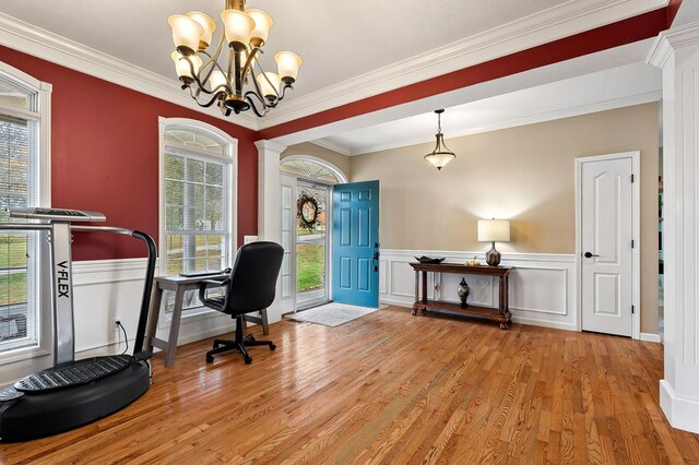 home office featuring light wood-type flooring, wainscoting, crown molding, and ornate columns