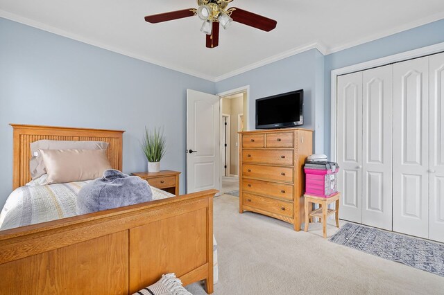 bedroom featuring ornamental molding, a closet, a ceiling fan, and light colored carpet