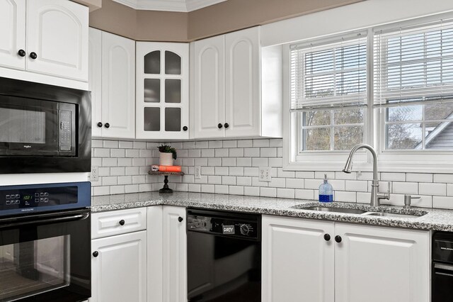 kitchen with a sink, white cabinetry, decorative backsplash, black appliances, and glass insert cabinets