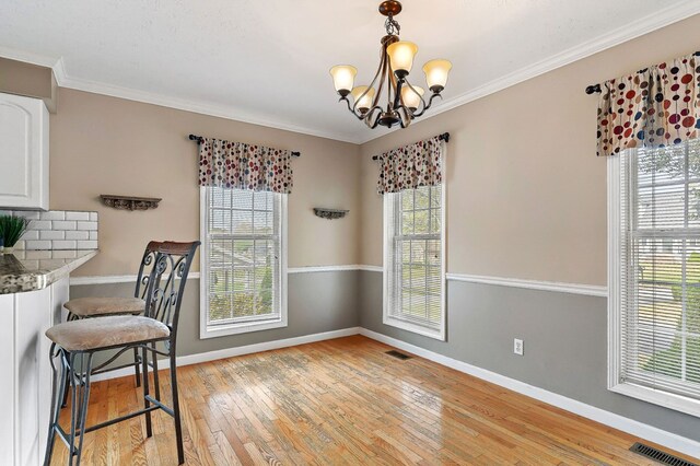 dining room with light wood-type flooring, visible vents, and crown molding