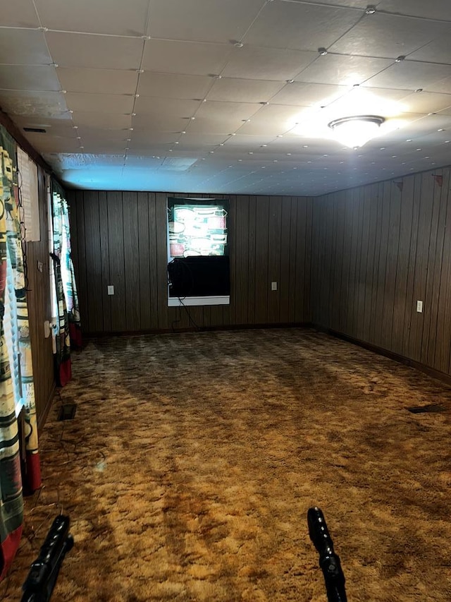 empty room featuring dark carpet and wood walls