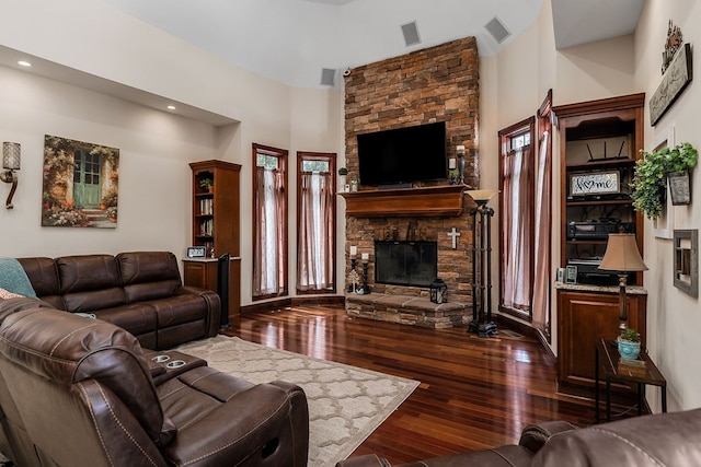 living room with a fireplace, visible vents, and dark wood-type flooring