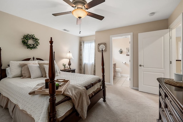 bedroom with light carpet, visible vents, baseboards, a ceiling fan, and ensuite bath