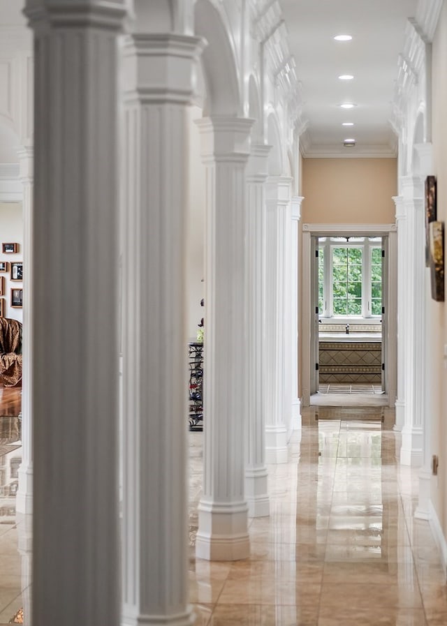 corridor with arched walkways, marble finish floor, decorative columns, recessed lighting, and ornamental molding