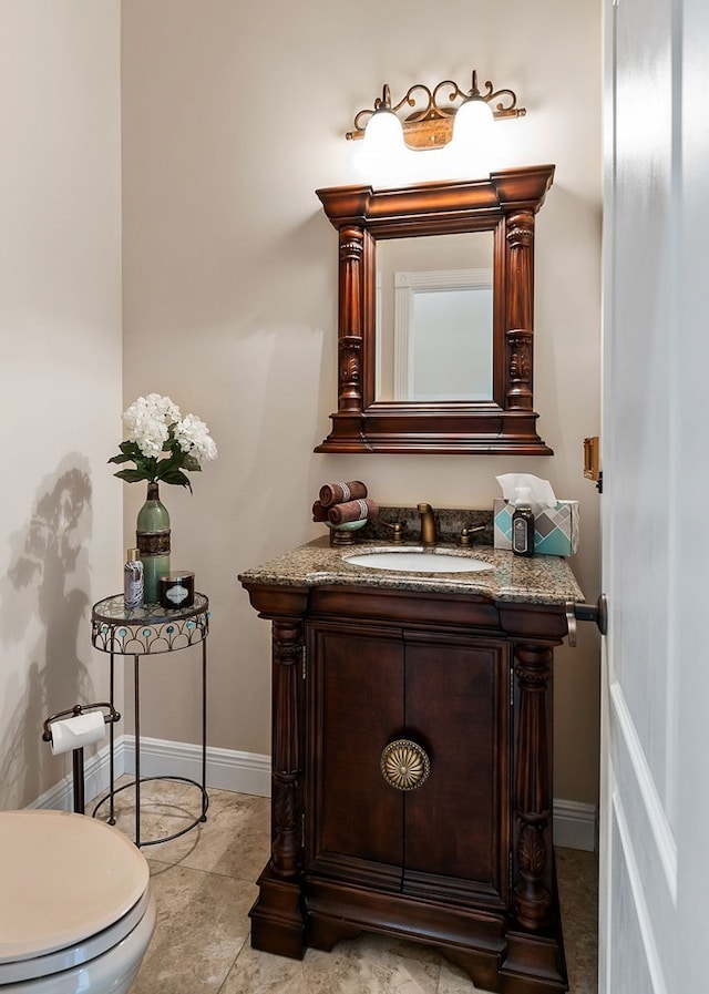 half bathroom featuring toilet, vanity, and baseboards