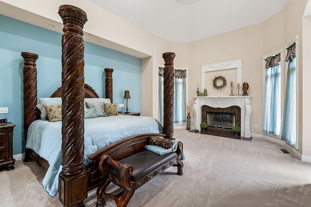 bedroom featuring light colored carpet, visible vents, a fireplace, and baseboards