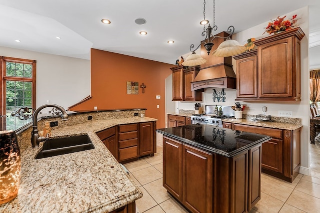 kitchen featuring custom range hood, decorative light fixtures, light stone countertops, high end stainless steel range oven, and a sink