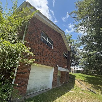 5740 S York Hwy, Clarkrange, TN 38553 - view of home's exterior featuring a garage, brick siding, and a lawn