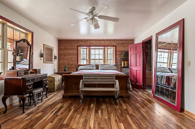 bedroom featuring dark wood-type flooring, wood walls, and a ceiling fan