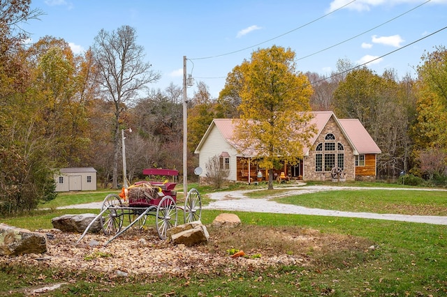 view of front of house featuring an outbuilding, stone siding, a front lawn, and a shed