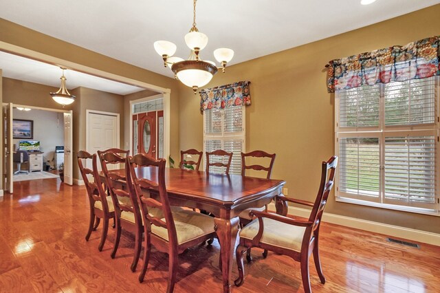 dining area with baseboards, visible vents, and wood finished floors