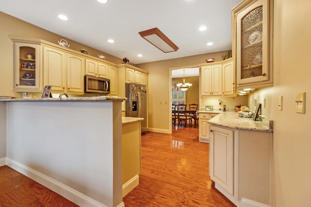 kitchen featuring cream cabinets, glass insert cabinets, and stainless steel appliances