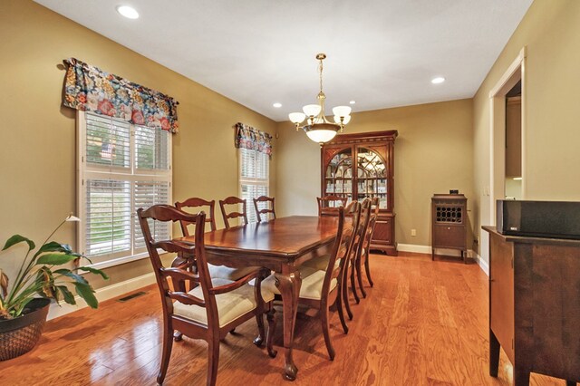 dining room featuring light wood-style floors, a chandelier, visible vents, and baseboards