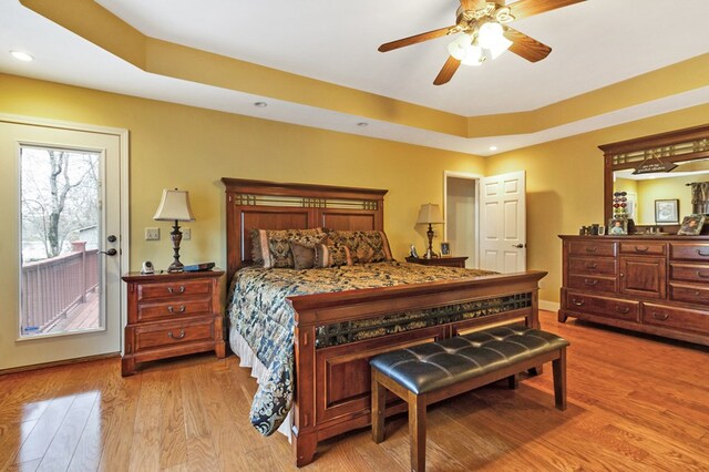 bedroom featuring light wood-style flooring, recessed lighting, baseboards, access to outside, and a tray ceiling