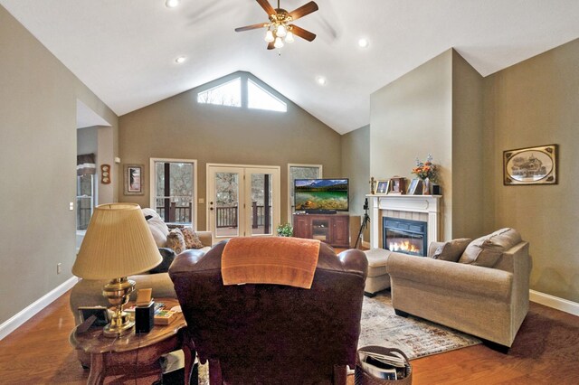 living room featuring ceiling fan, a fireplace, baseboards, and wood finished floors