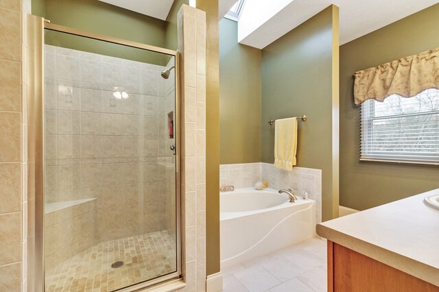 bathroom with tile patterned flooring, a skylight, vanity, a shower stall, and a bath