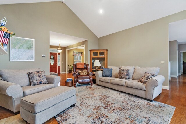 living room with high vaulted ceiling, wood finished floors, and baseboards