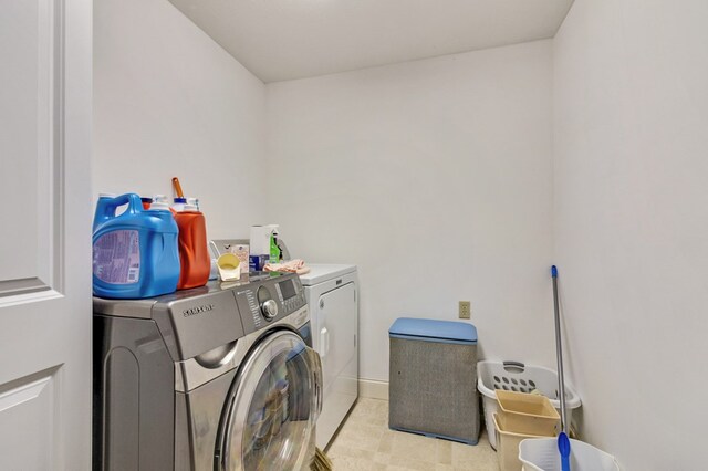 laundry area with laundry area, light tile patterned floors, baseboards, and separate washer and dryer