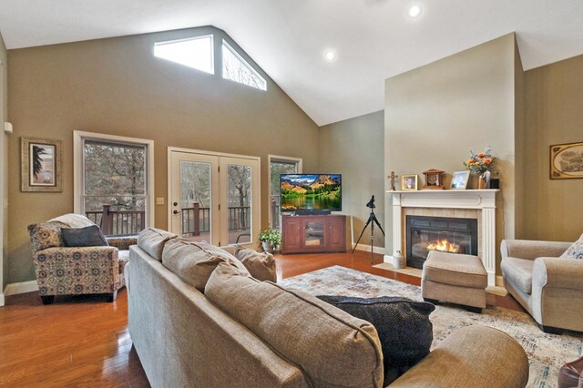 living area featuring recessed lighting, a tiled fireplace, wood finished floors, high vaulted ceiling, and baseboards