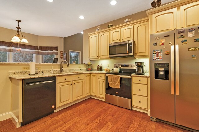 kitchen featuring recessed lighting, stainless steel appliances, wood finished floors, a sink, and decorative light fixtures