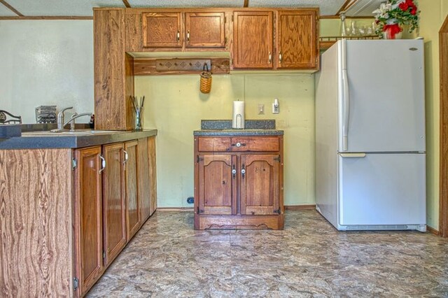 5088 Baptist Ridge Rd, Hilham, TN 38568 - kitchen featuring freestanding refrigerator, brown cabinets, and dark countertops