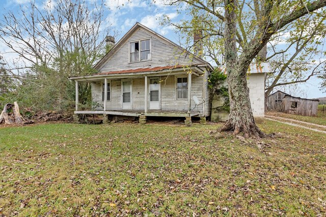 view of front of property featuring a porch, a front lawn, and a chimney