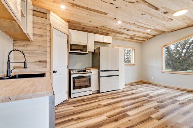 kitchen with wooden ceiling, a sink, stainless steel range with electric cooktop, light countertops, and freestanding refrigerator