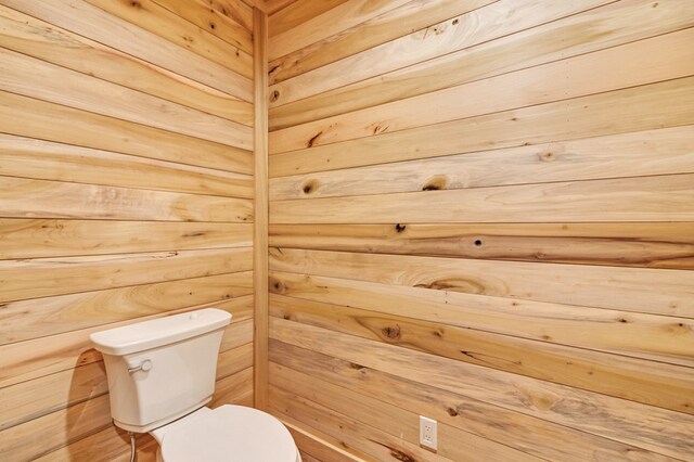 bathroom with toilet and wood walls