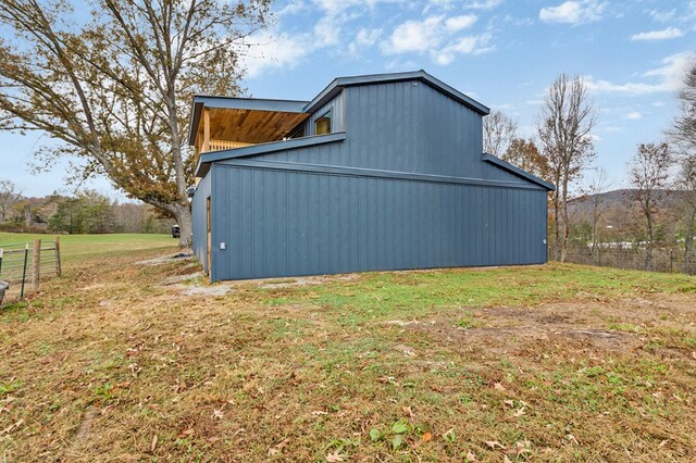 view of side of home with a detached garage, fence, an outdoor structure, and a yard