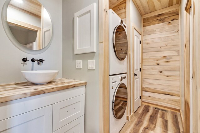 washroom featuring a sink, laundry area, light wood finished floors, and stacked washer / dryer