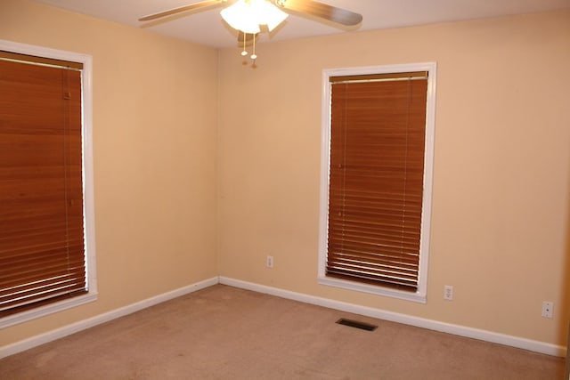 unfurnished room featuring light carpet, baseboards, visible vents, and ceiling fan