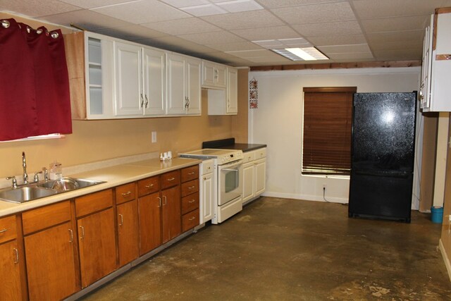 kitchen with light countertops, electric range, brown cabinetry, freestanding refrigerator, and a sink