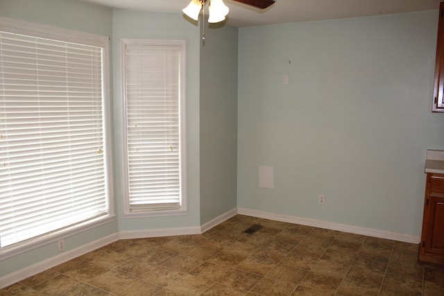 unfurnished room with ceiling fan, visible vents, and baseboards