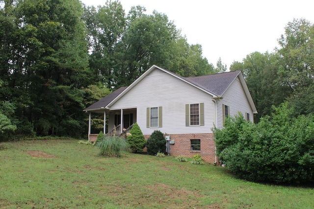 view of home's exterior with brick siding, a porch, and a yard