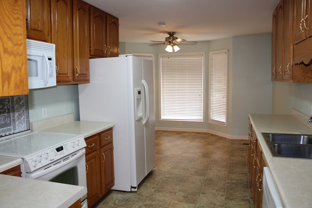 kitchen featuring white appliances, baseboards, brown cabinets, light countertops, and a sink