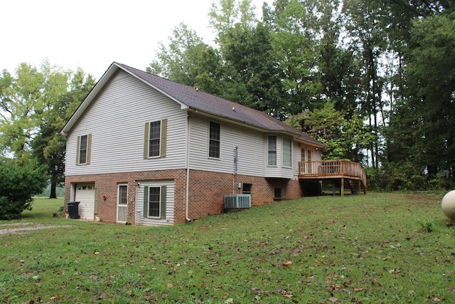 view of home's exterior featuring a deck, central AC unit, an attached garage, brick siding, and a yard