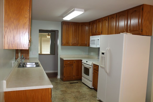 kitchen featuring white appliances, baseboards, brown cabinets, light countertops, and a sink