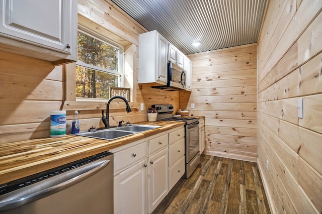 kitchen featuring stainless steel appliances, wood walls, and white cabinets