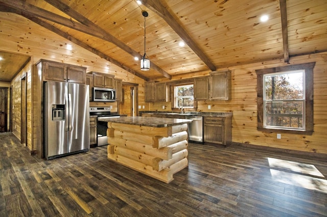 kitchen with lofted ceiling with beams, stainless steel appliances, a kitchen island, dark countertops, and decorative light fixtures