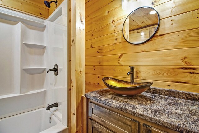 bathroom with wooden walls, vanity, and shower / bathtub combination