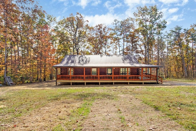 view of front facade with metal roof, log exterior, and a front lawn