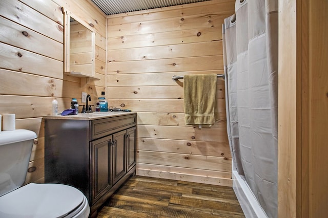 bathroom with toilet, wooden walls, wood finished floors, and vanity